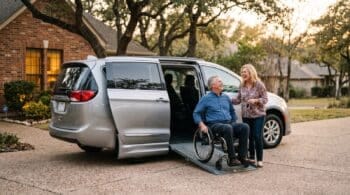 Man in a wheelchair at the ramp of a wheelchair accessible minivan in a Texas driveway, talking with his wife